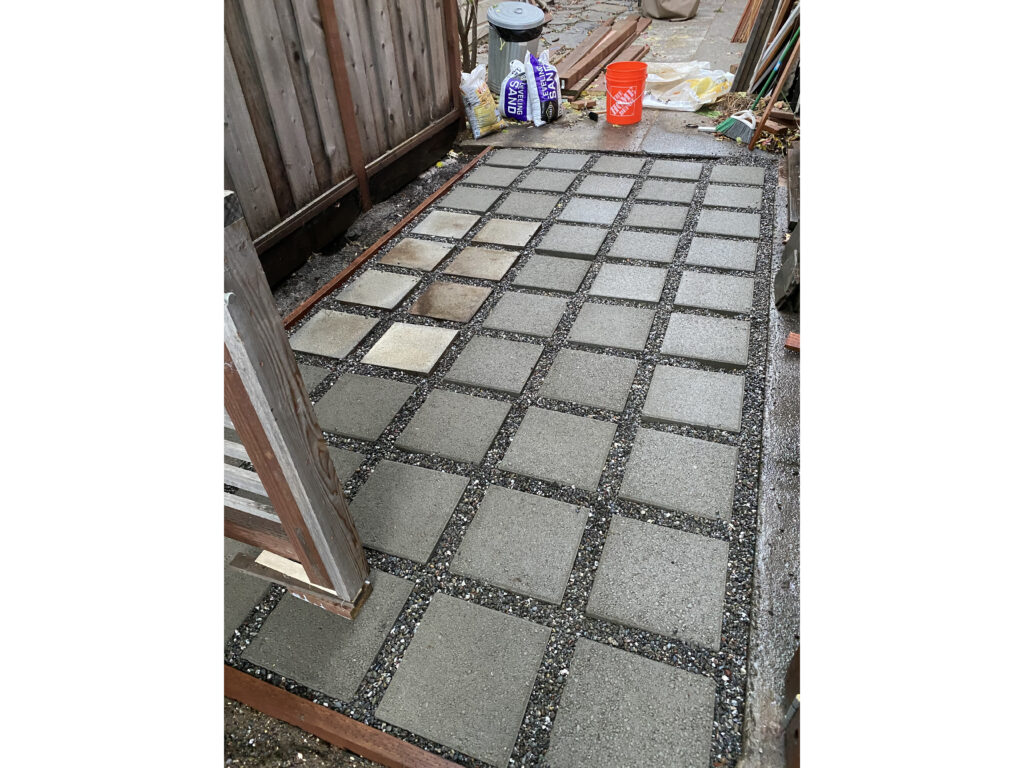 Square pavers installed in a grid pattern with pea gravel in the gaps between them