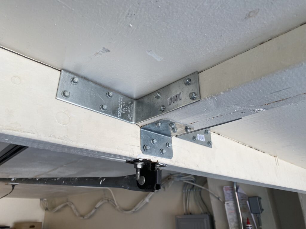 Steel brackets reinforcing a garage door that had broken apart after years of stress from the garage door opener