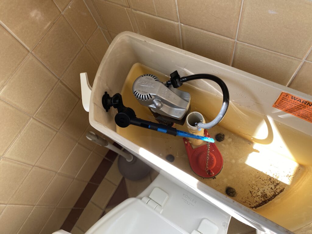 Open toilet tank showing newly installed fill valve