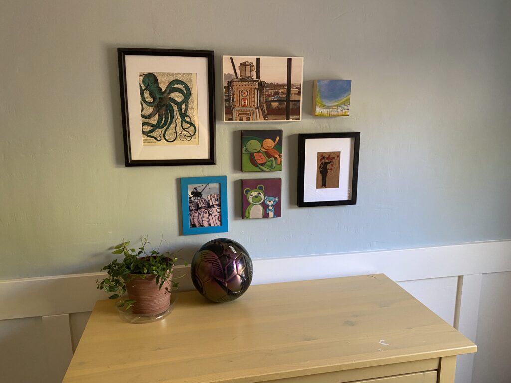 A gallery-wall style arrangement of seven small framed prints on a bedroom wall